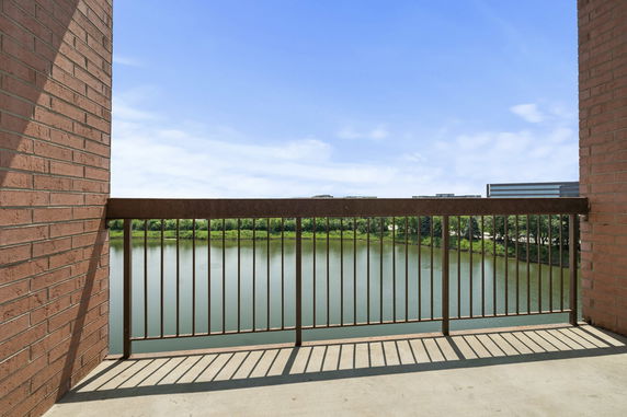 View from a balcony overlooking a body of water and distant buildings.