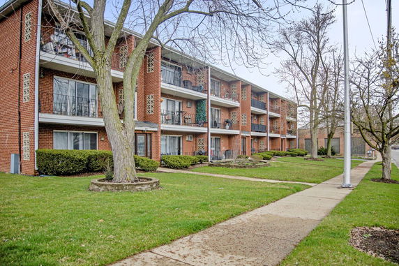 Front view of a multi-story brick apartment building with balconies.