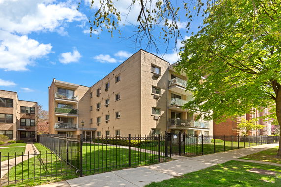 Front view of a multi-story brick apartment building with balconies.