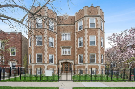 Front view of a three-story brick apartment building with decorative elements.