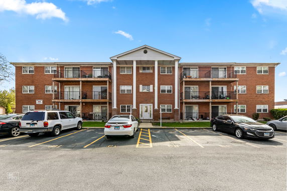 Front view of a three-story brick apartment building with balconies.