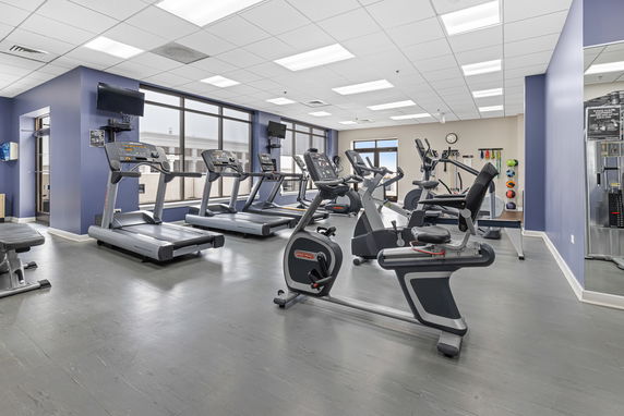 Gym area with various exercise equipment including treadmills and stationary bikes.