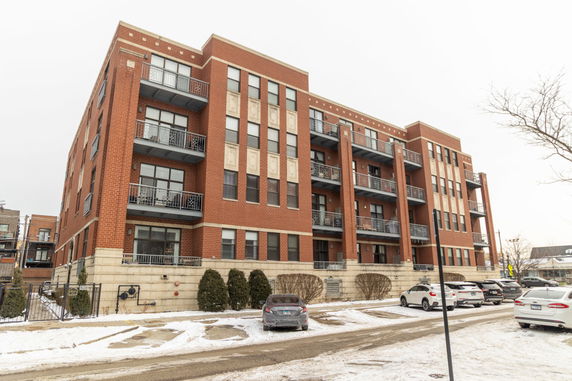 Front view of a multi-story brick apartment building with balconies.