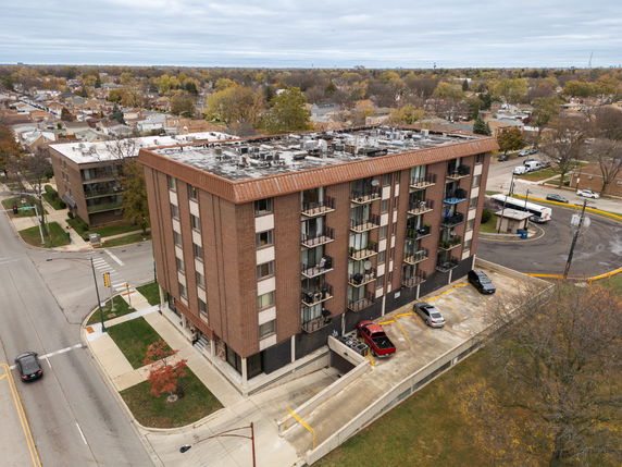 Front view of a multi-story apartment building with balconies and rooftop features.