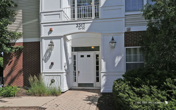 Front view of a building entrance with a white door and lantern-style lights.