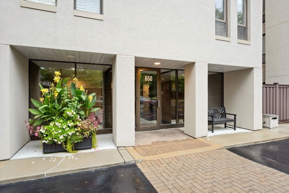 Front view of a building entrance with glass doors and large planters.