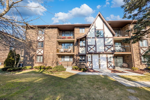 Front view of a multi-story apartment building with brick and white paneling.