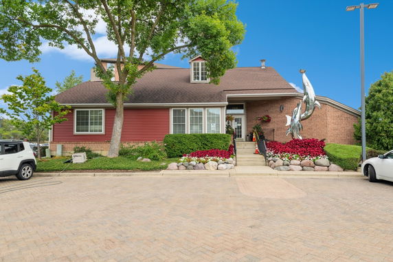 Front view of a house with a red facade and a brown roof, featuring a metal dolphin sculpture.