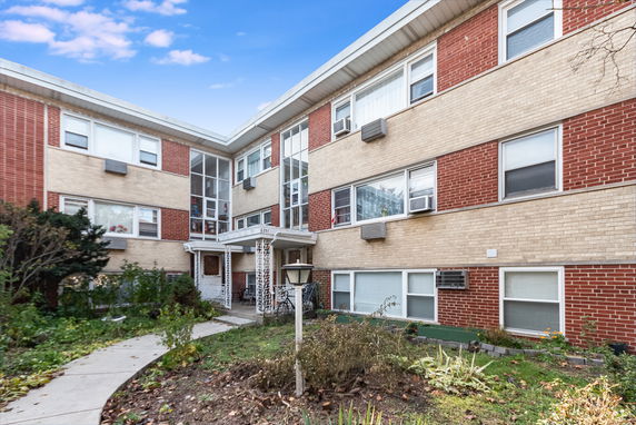 Front view of a three-story brick apartment building with multiple windows and entryway.