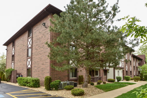 Front view of a three-story brick apartment building with large windows and decorative white paneling.
