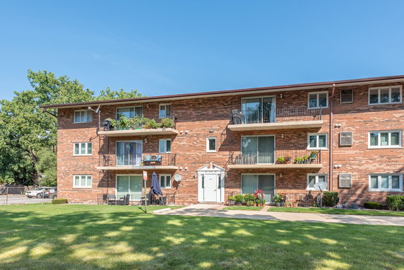 Front view of a multi-story brick apartment building with balconies.
