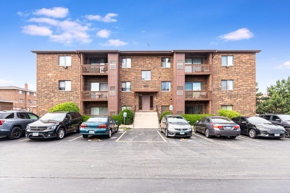 Front view of a multi-story brick apartment building with balconies.