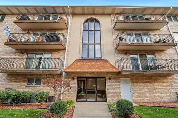 Front view of a multi-story building with balconies and large arched window.