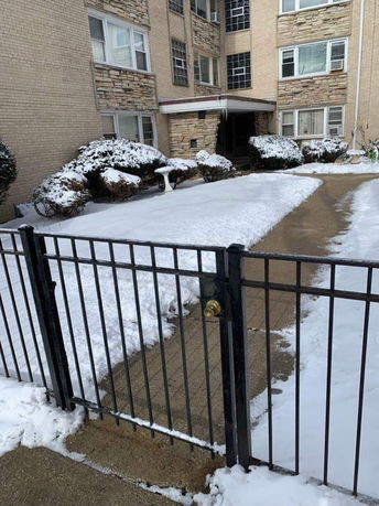 Front view of a multi-story building with brick and stone facade covered in snow.
