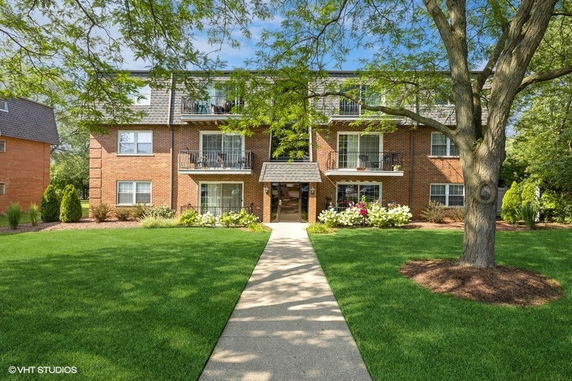 Front view of a multi-story brick apartment building with balconies.