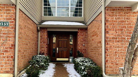 Front view of a house entrance with brick walls and a wooden door.