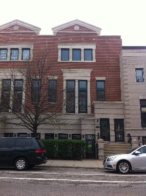 Front view of a multi-story brick townhouse with large windows.