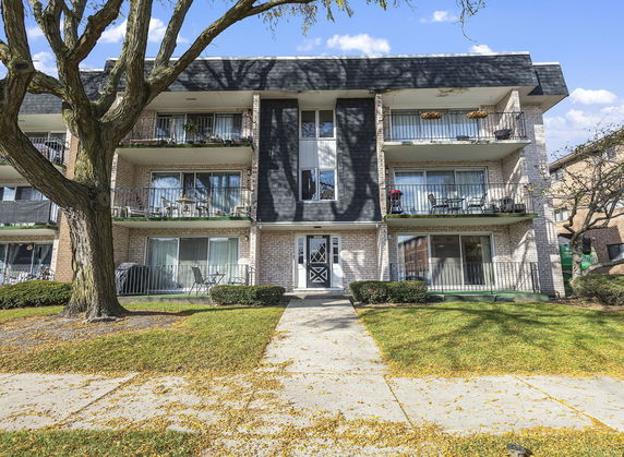 Front view of a three-story apartment building with balconies