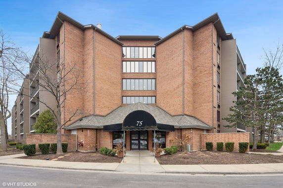 Front view of a multi-story brick building with large windows and an arched entrance.