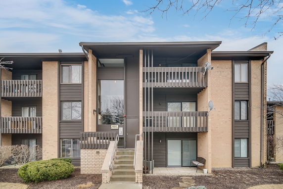Front view of a multi-story residential building with balconies and a central entrance.
