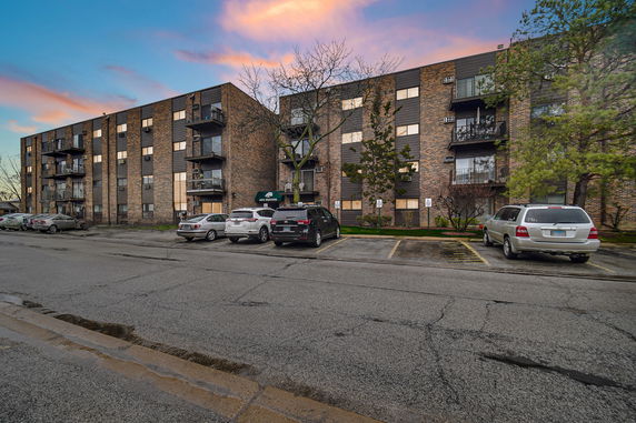 Front view of a multi-story apartment building with a brick exterior and balconies.