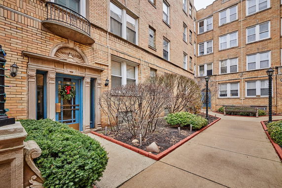 Front view of a multi-story brick apartment building with a decorated entrance.