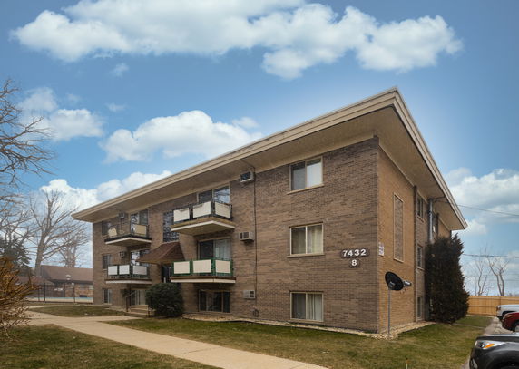 Front view of a three-story apartment building with balconies.