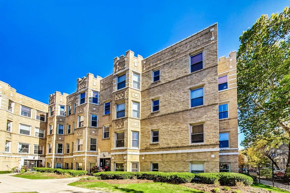 Front view of a multi-story brick apartment building with decorative architectural elements.