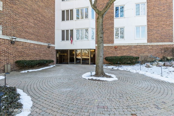 Front view of a multi-story brick building with a main entrance and circular driveway.