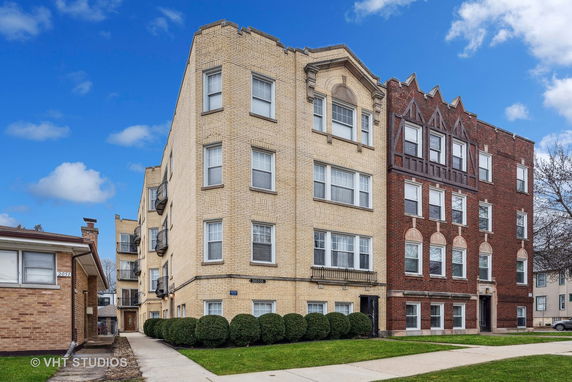 Front view of a multi-story apartment building with a yellow brick facade.