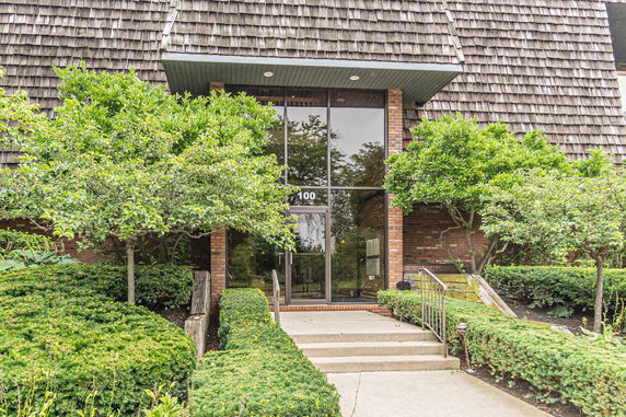 Front view of a brick building with large glass entrance and shingle roof.