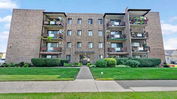 Front view of a multi-story brick apartment building with balconies.