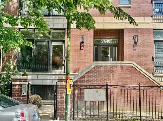 Front view of a brick-faced building with a stair entry and metal railing.