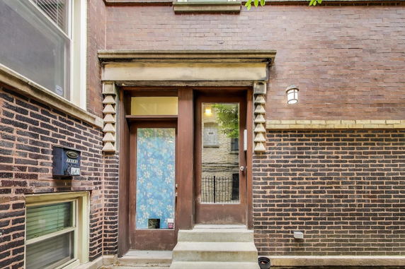Front view of a brick building entrance with a decorative design around the door.