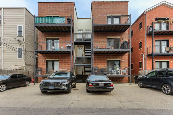 Front view of a multi-story brick apartment building with balconies.