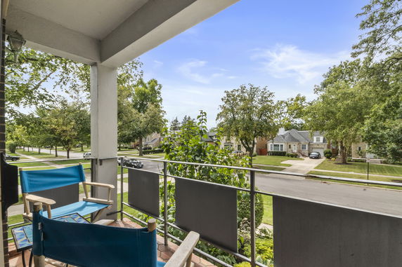 Panoramic view from a balcony overlooking a suburban street with houses and trees.