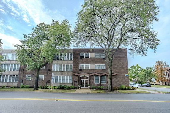 Front view of a three-story brick building with large windows.