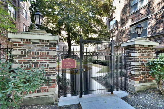 Front view of a brick building entrance with a wrought iron gate and lanterns.