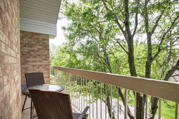 View from a balcony with trees visible in the background and patio furniture present.