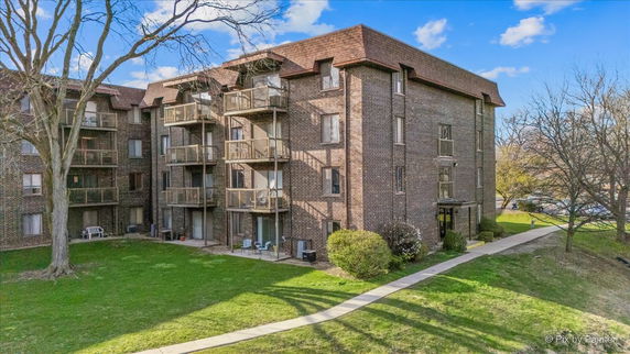 Front view of a multi-story brick apartment building with balconies.
