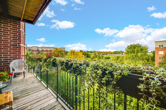 Balcony view overlooking a landscaped area with greenery and distant buildings.