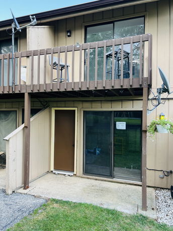 Rear view of a two-story house with a balcony and sliding doors on the ground floor.