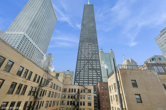 Front view of a tall skyscraper surrounded by other buildings.