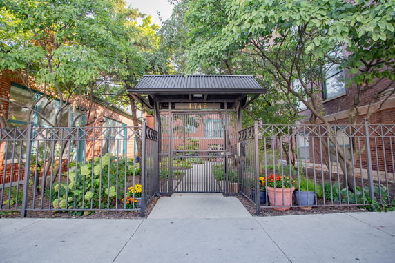 Front view of a gated entrance to a building with a landscaped garden.