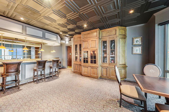 Interior view of a room with a bar, high chairs, and cabinetry.