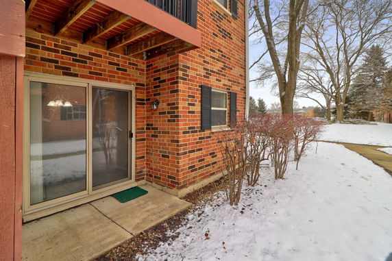 Corner view of a brick building with sliding glass door and windows.