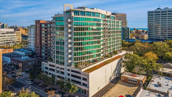 Front view of a multi-story building with green glass windows and a rooftop garden.