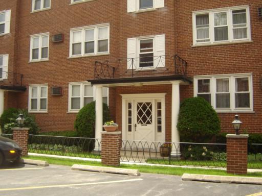 Front view of a multi-story brick building with a white door entrance and multiple windows.