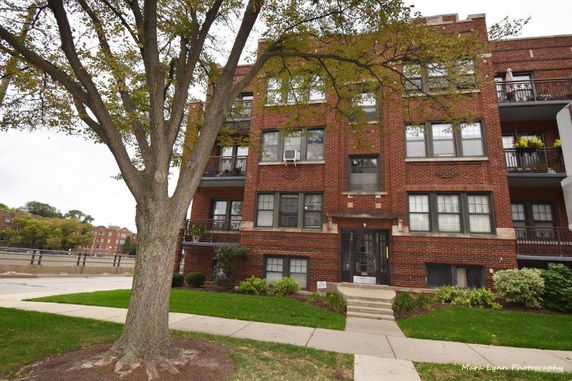 Front view of a multi-story brick apartment building with balconies.
