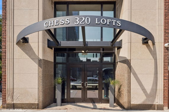 Front view of an entrance to a building labeled 'CHESS 320 LOFTS' with glass doors.